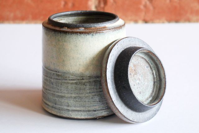 A small jar with a slightly wide base and angular walls sloping in slightly
